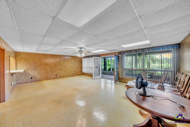 interior space featuring wooden walls, ceiling fan, and a paneled ceiling
