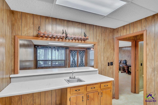 bar featuring wood walls, a sink, and a drop ceiling