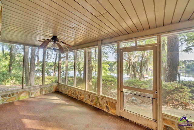 unfurnished sunroom featuring a water view and a ceiling fan