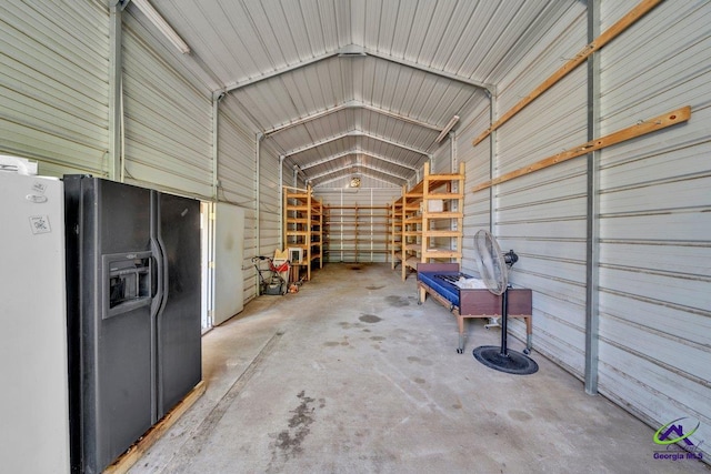 interior space with metal wall and black fridge with ice dispenser