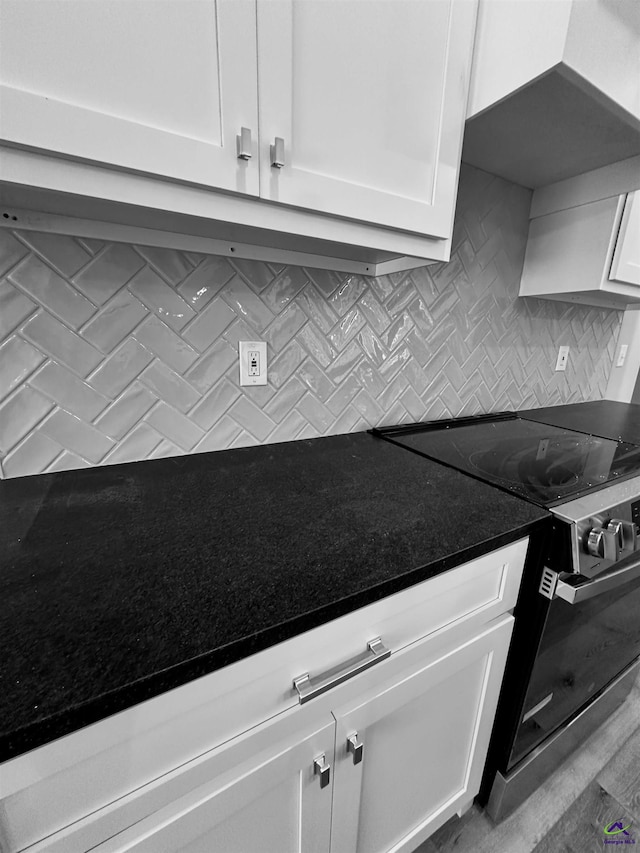 kitchen featuring backsplash, range with electric cooktop, and white cabinetry