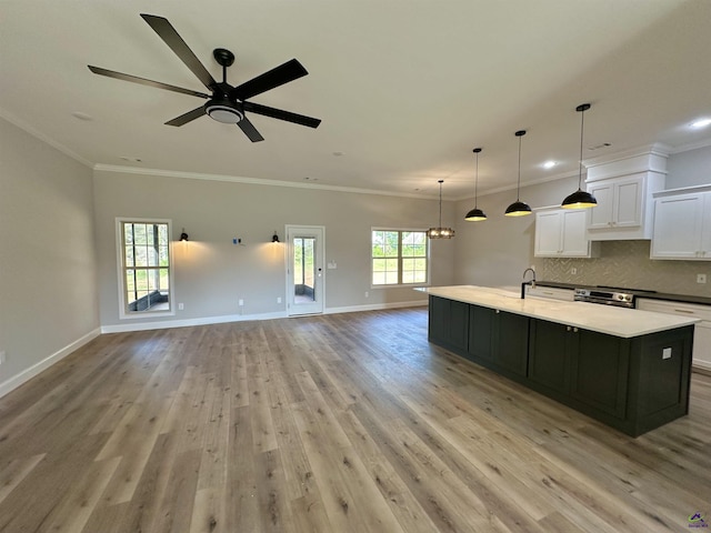 kitchen with stainless steel range with electric stovetop, light wood-style flooring, white cabinetry, open floor plan, and a center island with sink