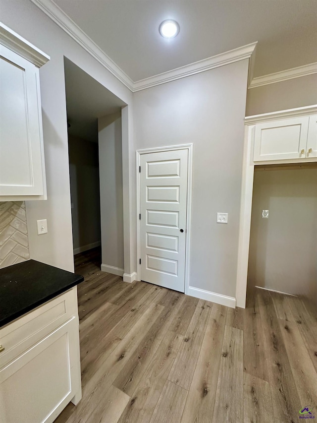 interior space featuring crown molding, baseboards, and light wood-style floors