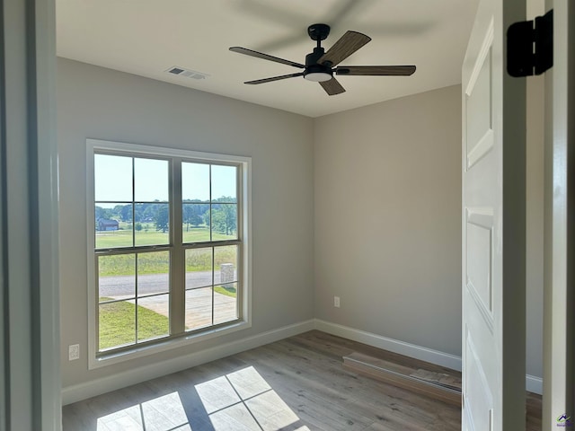 unfurnished room with baseboards, plenty of natural light, wood finished floors, and visible vents