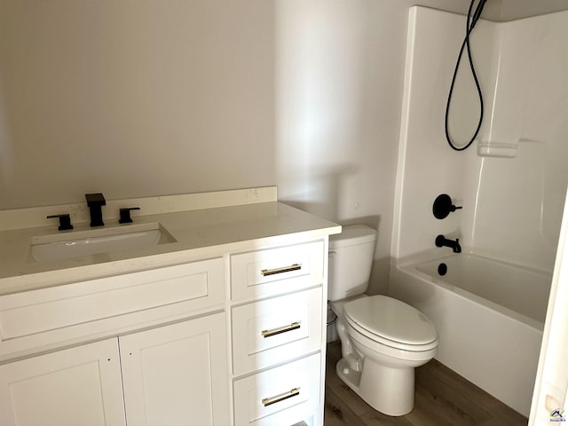 bathroom with vanity, wood finished floors, toilet, and shower / washtub combination