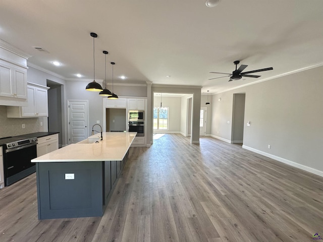 kitchen featuring ornamental molding, open floor plan, ceiling fan, white cabinets, and a sink