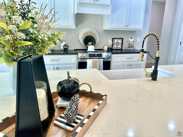 84 Camden Way, Hawkinsville, GA 31036 - kitchen with stainless steel range with electric stovetop, a sink, backsplash, white cabinetry, and dark stone countertops