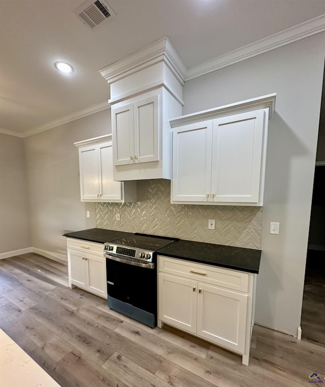 kitchen with visible vents, crown molding, dark countertops, tasteful backsplash, and stainless steel range with electric cooktop