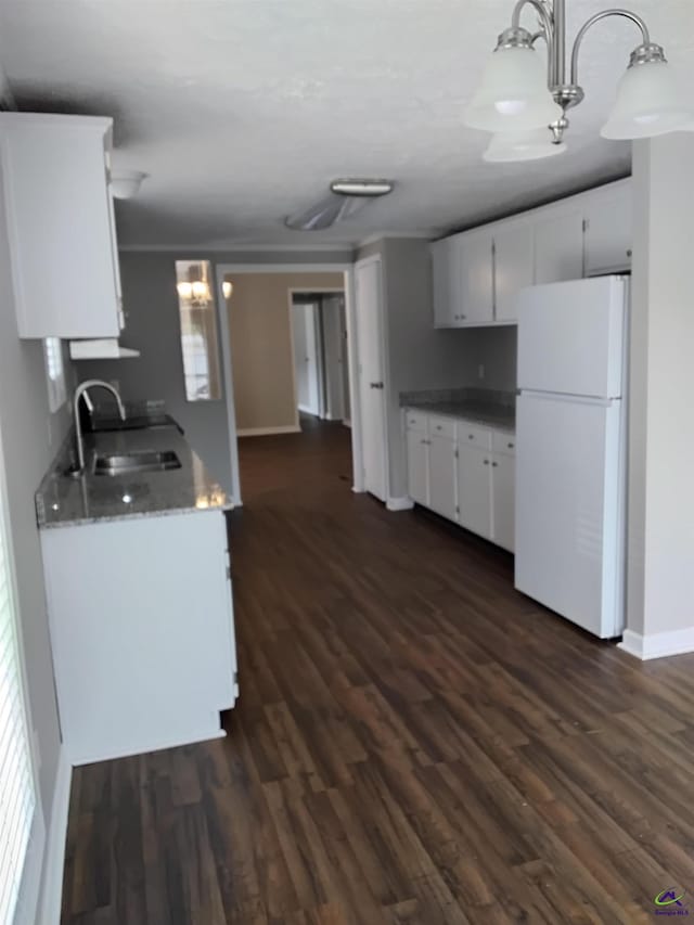 kitchen featuring freestanding refrigerator, white cabinetry, a sink, and dark wood-type flooring