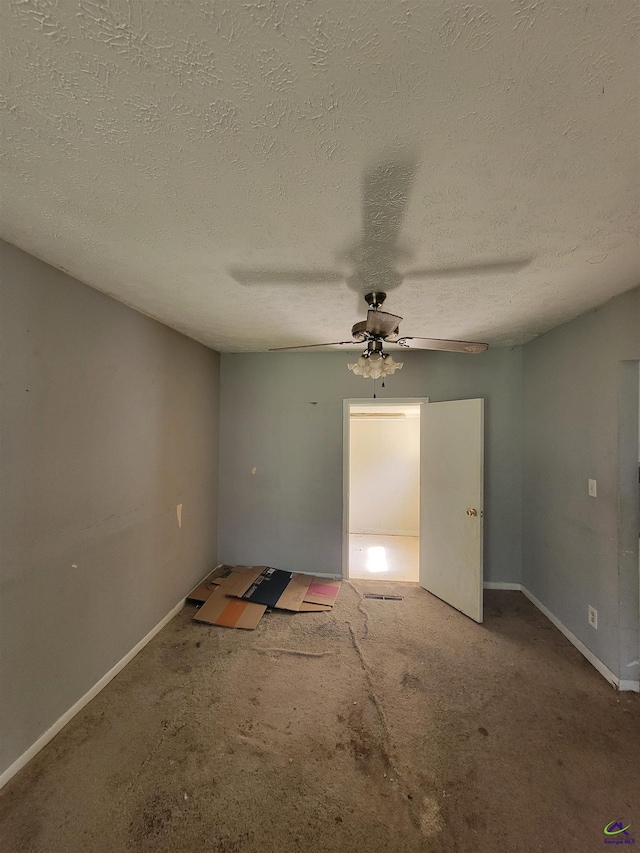 carpeted spare room featuring baseboards, a ceiling fan, and a textured ceiling