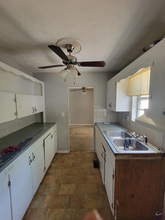 kitchen with a sink, white cabinetry, ceiling fan, and a textured ceiling