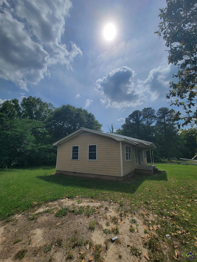 view of side of property with a lawn and crawl space