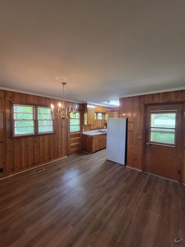 interior space with freestanding refrigerator, dark wood finished floors, brown cabinets, and a chandelier