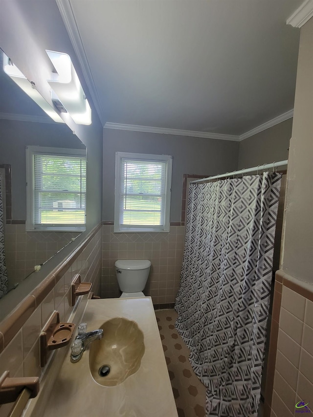 full bath with a sink, tile walls, wainscoting, and toilet