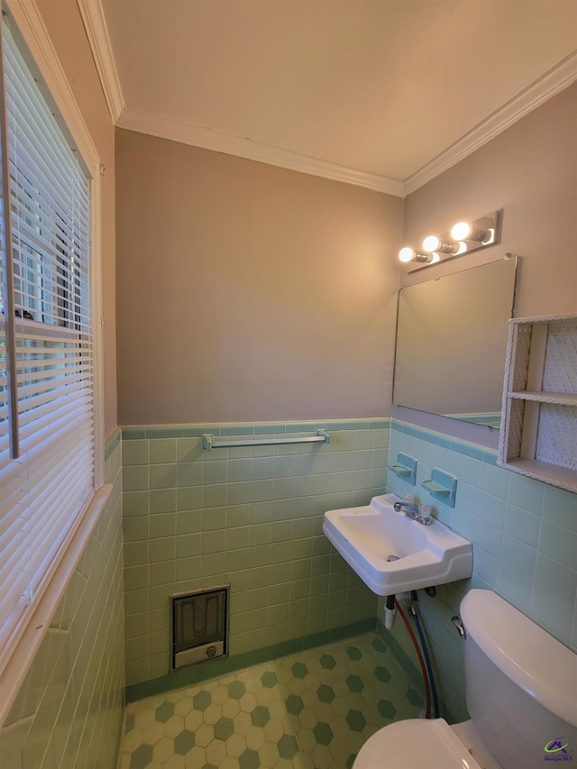 half bath with crown molding, toilet, tile walls, and wainscoting