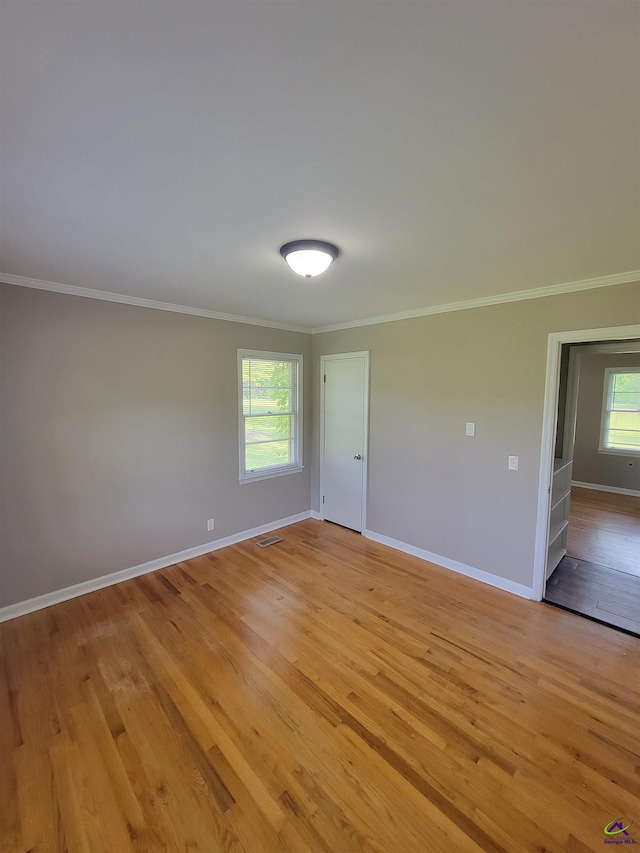 unfurnished room with crown molding, baseboards, and light wood-type flooring