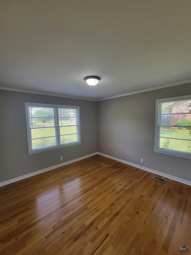 spare room featuring visible vents, ornamental molding, baseboards, and wood finished floors