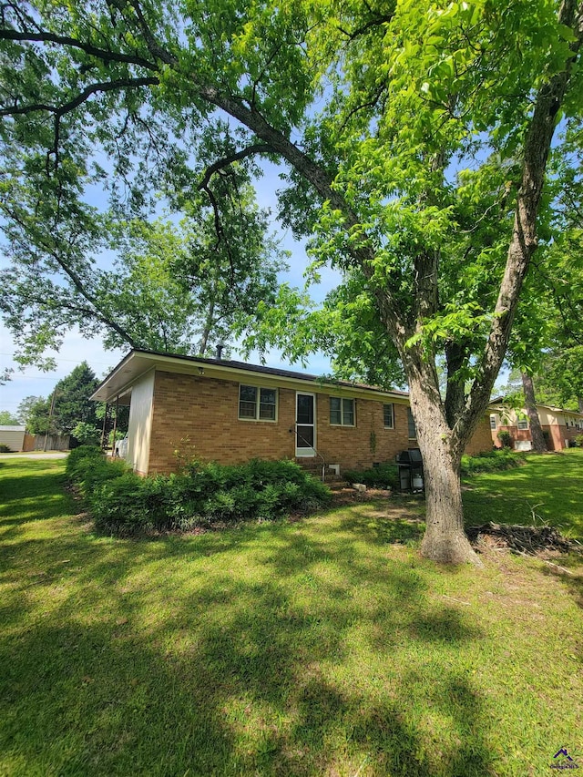 rear view of property with a lawn and brick siding