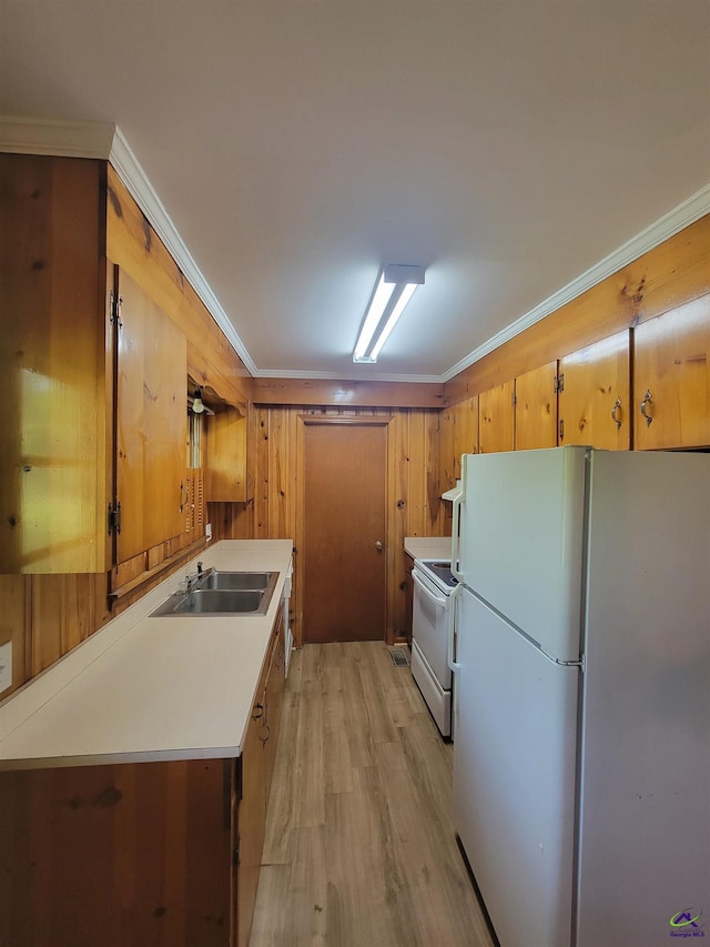 kitchen featuring crown molding, a sink, light countertops, light wood finished floors, and white appliances
