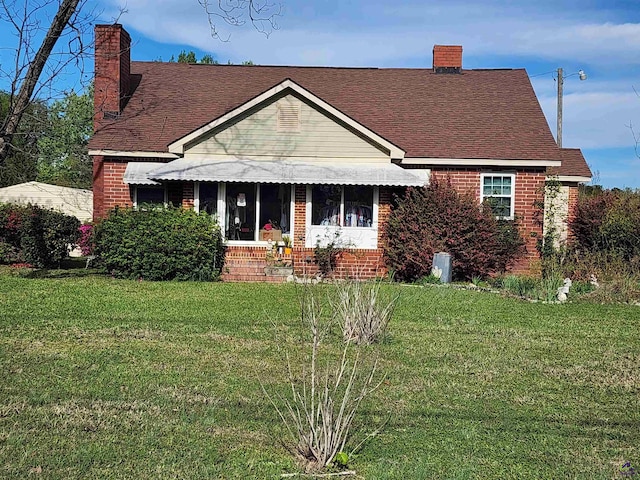 bungalow featuring brick siding, a chimney, and a front yard