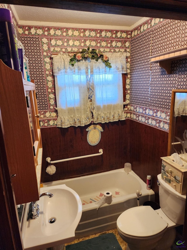 full bathroom with a sink, a bathing tub, toilet, wallpapered walls, and ornamental molding