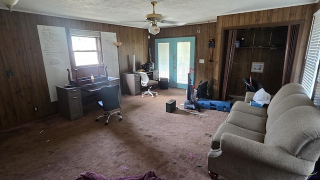 office area with ceiling fan, french doors, a textured ceiling, wood walls, and carpet