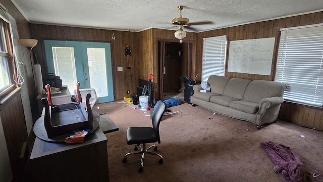 office area featuring wood walls, carpet, a ceiling fan, and a textured ceiling