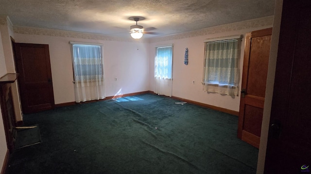 spare room featuring baseboards, ceiling fan, dark carpet, and a textured ceiling