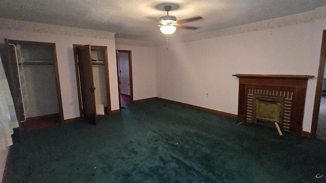 interior space featuring baseboards, ceiling fan, dark carpet, and a fireplace