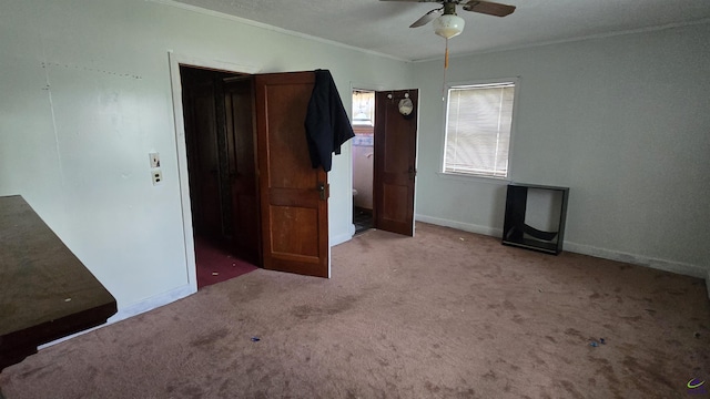 unfurnished bedroom featuring crown molding, carpet, ceiling fan, and baseboards