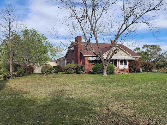 view of side of property featuring a lawn, brick siding, and a chimney