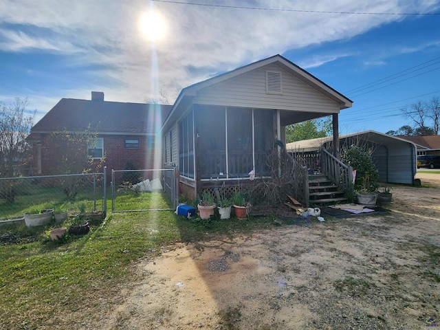 rear view of property featuring fence, a sunroom, a gate, a carport, and driveway