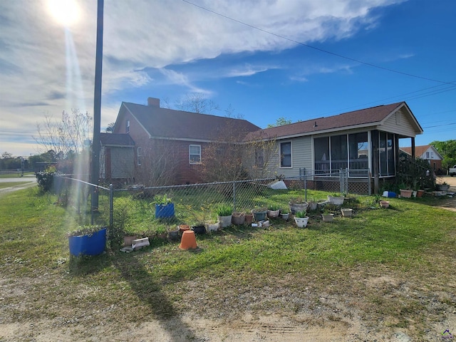 rear view of property with fence, a yard, and a sunroom