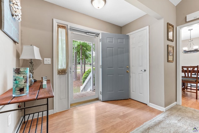 foyer entrance featuring an inviting chandelier, baseboards, and wood finished floors