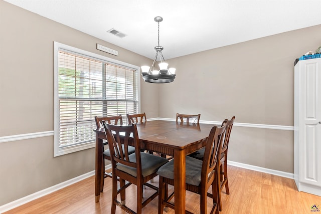 dining area with baseboards, a chandelier, light wood-style flooring, and visible vents