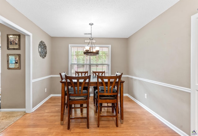 dining space featuring baseboards, light wood finished floors, a textured ceiling, and visible vents