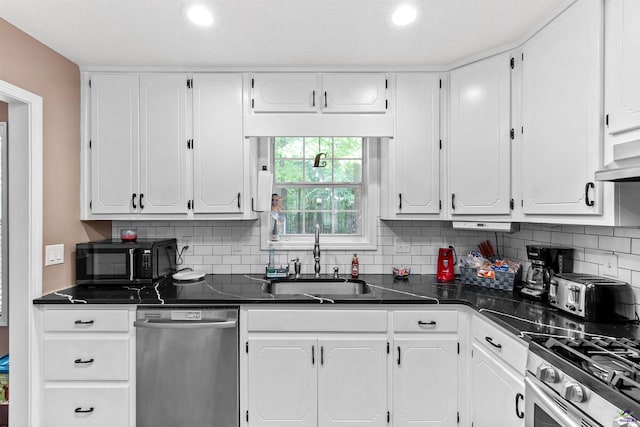kitchen featuring decorative backsplash, dark countertops, a sink, stainless steel appliances, and white cabinetry