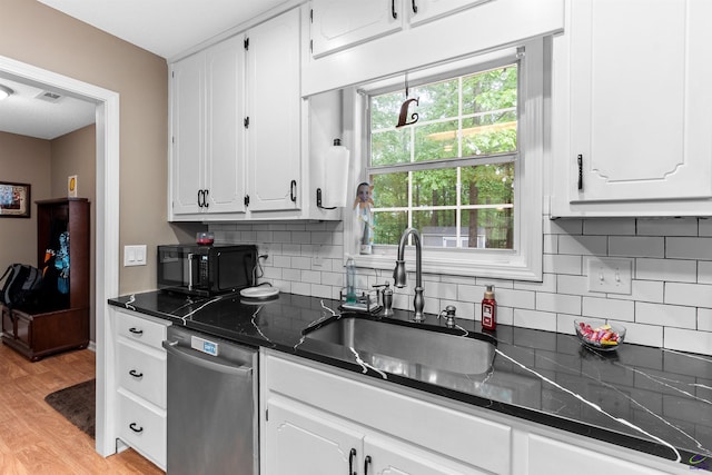 kitchen featuring dark countertops, black microwave, a sink, dishwasher, and white cabinetry