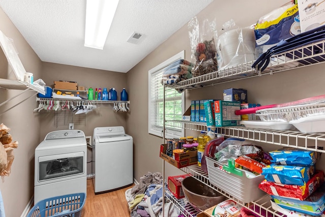 laundry room featuring laundry area, visible vents, wood finished floors, washer and dryer, and a textured ceiling