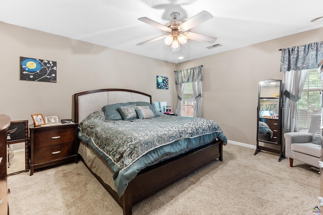 bedroom featuring visible vents, baseboards, ceiling fan, and light colored carpet
