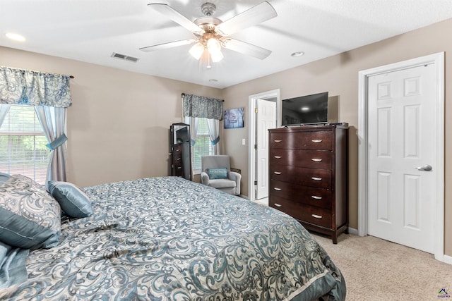 carpeted bedroom featuring baseboards, a ceiling fan, and visible vents