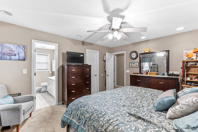 bedroom featuring light tile patterned floors, ensuite bathroom, light carpet, and ceiling fan