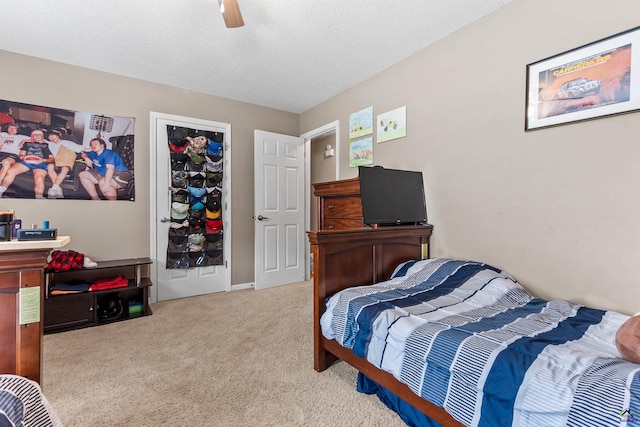carpeted bedroom featuring a ceiling fan and a textured ceiling