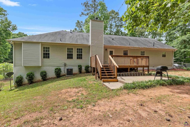 rear view of house with a chimney, a patio area, fence, and a deck