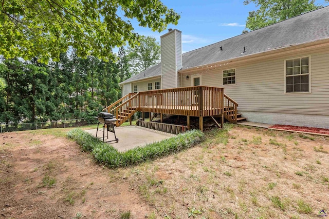 rear view of property with fence, a deck, a chimney, stairs, and a patio area