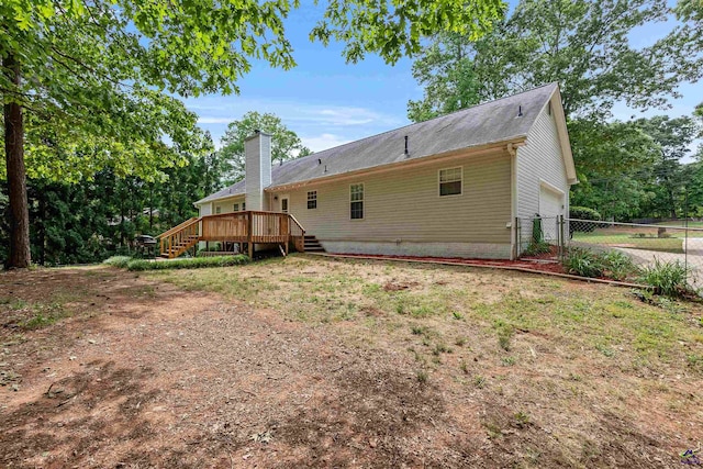 rear view of property featuring a deck, fence, stairs, and a garage