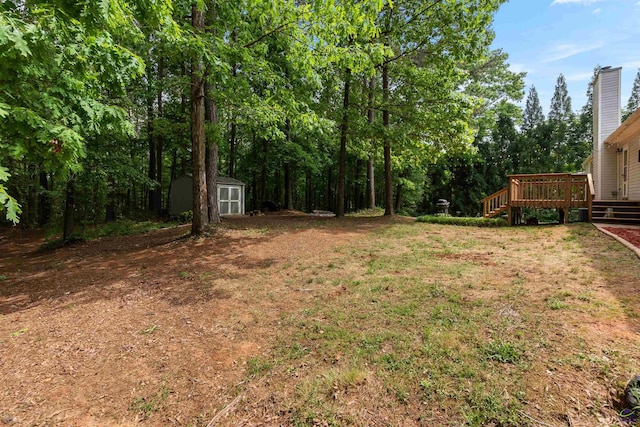 view of yard featuring an outbuilding, a wooden deck, and a shed