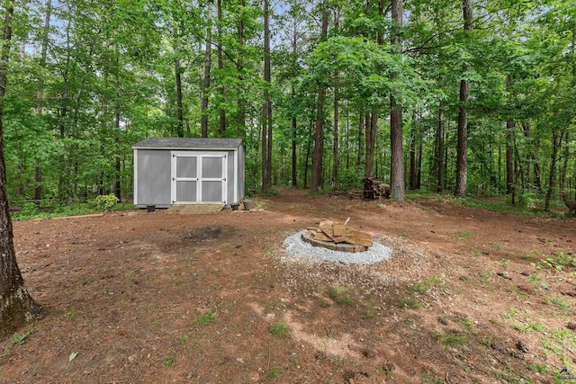 view of yard with a forest view, an outbuilding, and a shed
