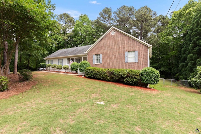 ranch-style house with brick siding, a front lawn, and fence