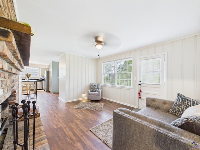 living area with baseboards, a ceiling fan, dark wood-style floors, and a fireplace